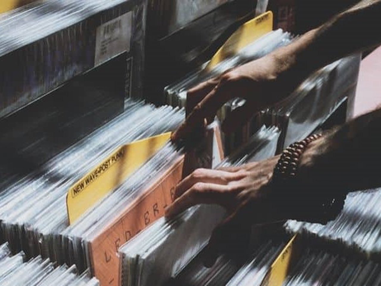 Hands flipping through vinyl records in a record-shop crate