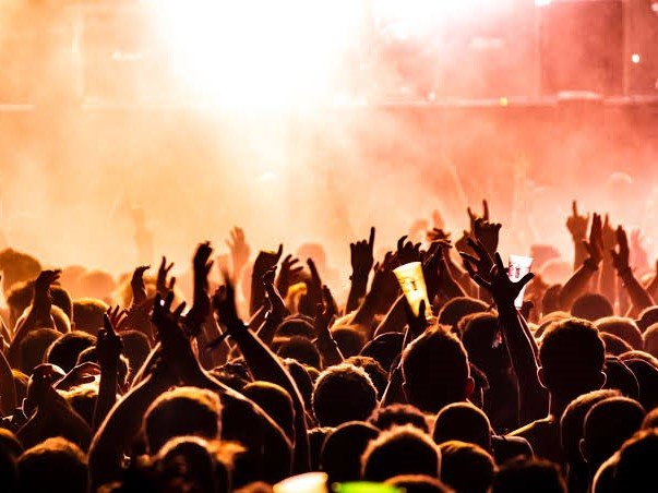 Concert crowd with raised hands lit by warm stage light
