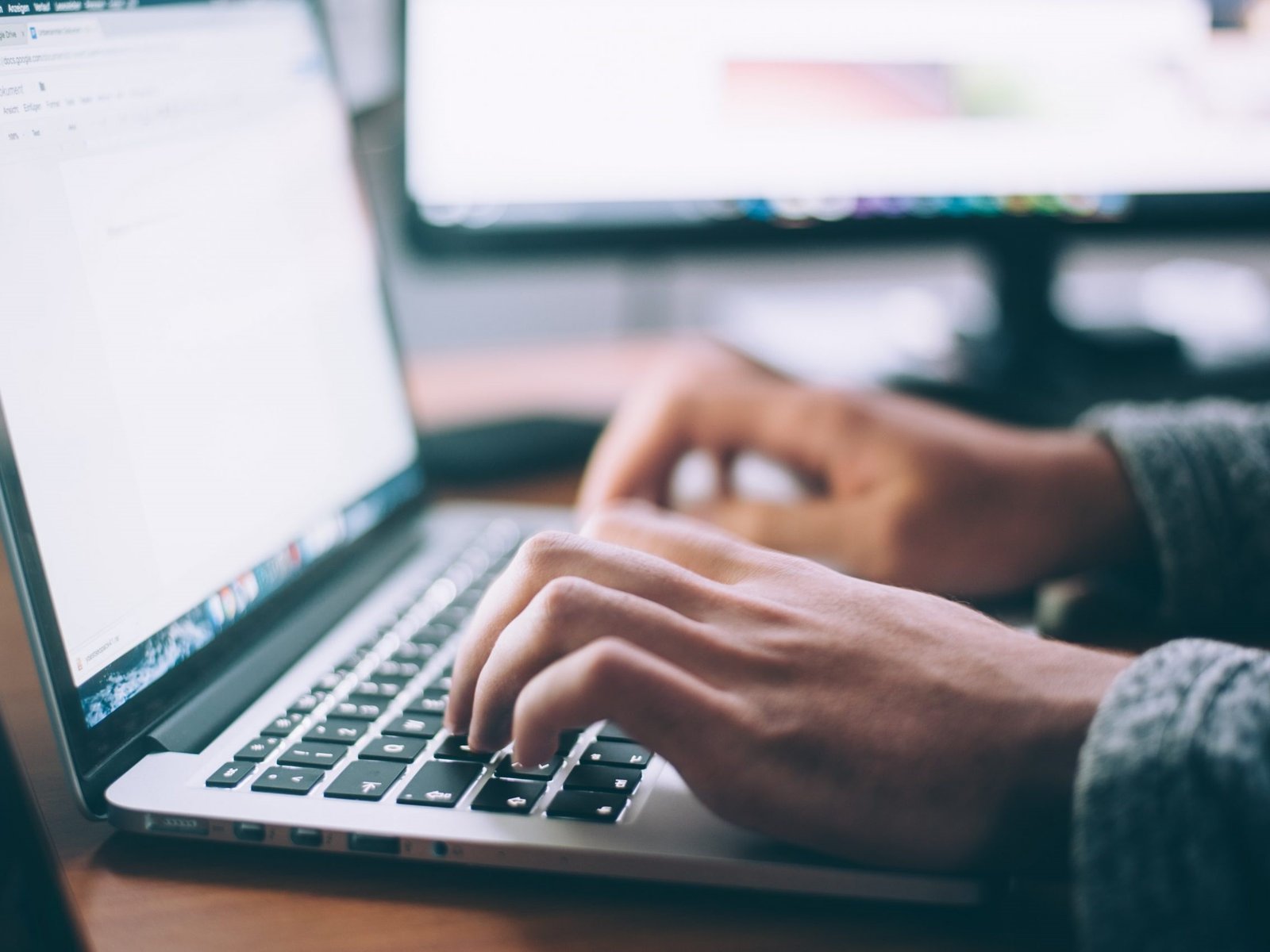 Hands typing on a laptop in a studio office